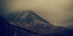 a large mountain covered in snow under a cloudy sky