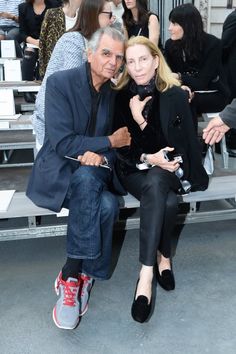 a man and woman sitting next to each other on a bench at a fashion show