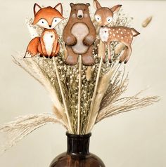 a brown vase filled with fake flowers and animals on top of it's stems