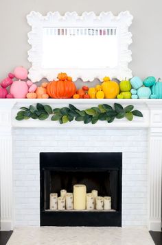 a fireplace decorated with candles, pumpkins and other colorful decorations on top of it