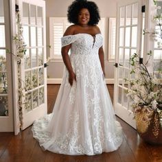 a woman in a white wedding dress standing on a wooden floor next to an open door