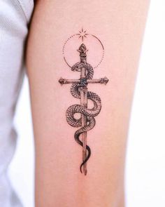 a woman's arm with a snake and dagger tattoo on it