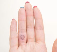 a person's hand with a small flower tattoo on the middle of their finger