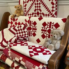 two teddy bears are sitting on a chair next to quilts and pillows in a room