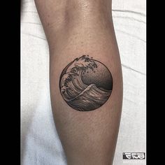 a black and white photo of a wave tattoo on the leg