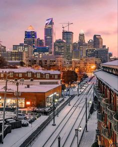 the city skyline is covered in snow as it sits on top of a train track