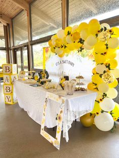 a white table topped with yellow and white balloons