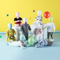 a group of plastic figures sitting on top of a white box with balloons floating around