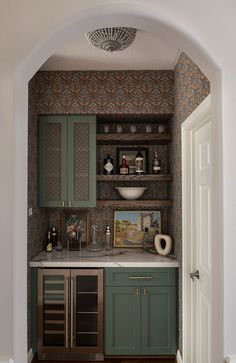 a kitchen with green cabinets and an arched doorway that leads to the dining room area