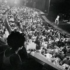 an audience is watching a man perform on stage in front of a large group of people