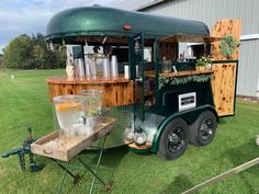 a green food truck parked on top of a lush green field