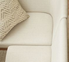 a close up of a white couch with a pillow on it's backrest