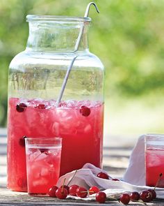 two glasses filled with ice and cherries next to a jar full of watermelon