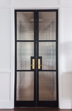 a black double door with gold handles in a white room