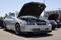 a silver car with its hood open in a parking lot