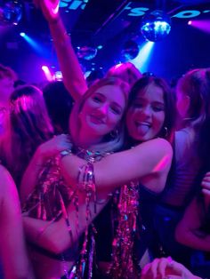 two women hugging each other at a party with disco lights on the ceiling behind them