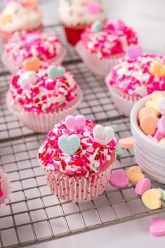 cupcakes with pink frosting and sprinkles on a cooling rack