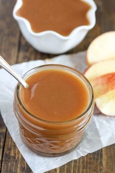 an apple and peanut butter spread in a jar with two apples on the table next to it