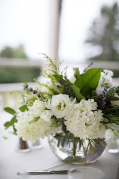 a vase filled with white flowers sitting on top of a table next to a knife and fork