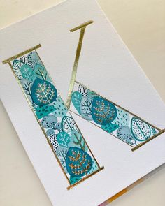 two pieces of paper with gold foil on them and some blue flowers in the middle