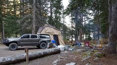 a truck parked in the woods next to a tent