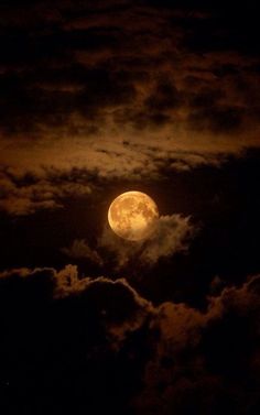 the full moon is shining brightly in the night sky with clouds and dark blue skies