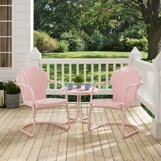 two pink chairs sitting on top of a wooden deck next to a table and potted plant