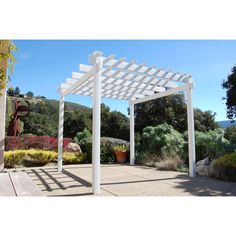 a white pergola sitting in the middle of a garden