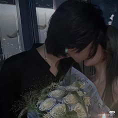 two people kissing each other while holding flowers