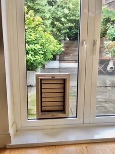 an empty dog crate sitting in the window sill next to a wooden floor and trees