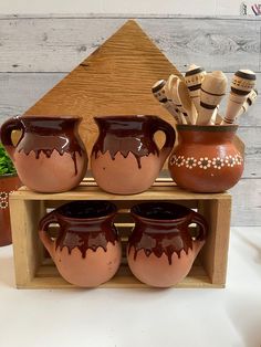 three brown vases sitting on top of a wooden shelf