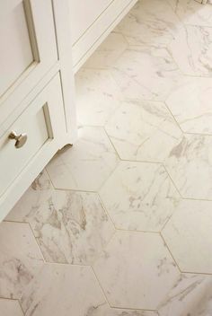 a bathroom with white marble flooring and drawers