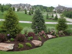 a lush green yard with rocks and flowers