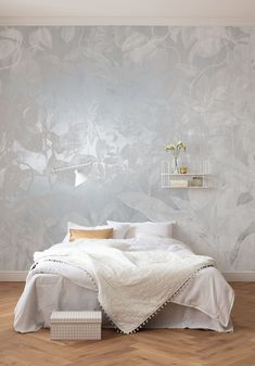 a white bed sitting in a bedroom next to a wall with flowers on top of it