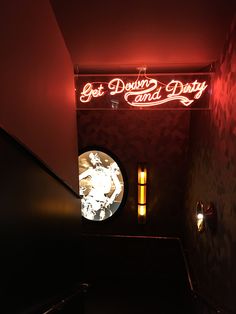 a red neon sign that says get down and dirty on the side of a wall