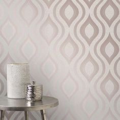 a white vase sitting on top of a table next to a wallpapered wall