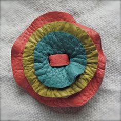 a red and yellow flower with a green center on a white cloth background, close up