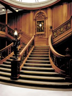 an ornate staircase in the middle of a building with a clock on it's side