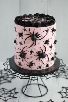 a pink cake decorated with black spider webs and pearls