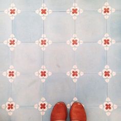 a pair of brown shoes sitting on top of a blue and white tile floor next to a wall