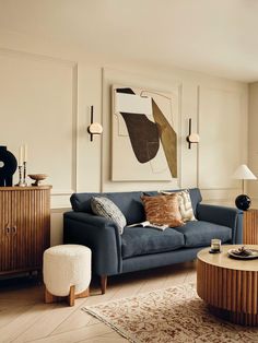 a living room with a blue couch and coffee table in front of a painting on the wall