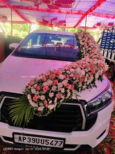 a white car with flowers on the hood and front grills is parked under an awning