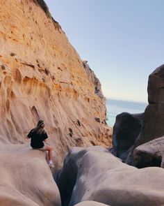 a person sitting on some rocks near the ocean