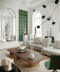 a living room filled with white furniture and lots of mirrors on the wall above it