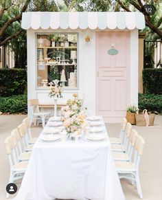 a table set up for a wedding with flowers and plates on it in front of a pink door