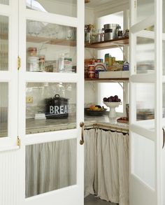 an open pantry with glass doors and shelves filled with food on top of the shelves