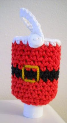 a knitted cup holder with a santa clause on it's side and a white button at the top