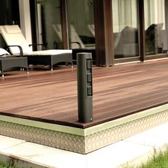 a wooden deck with an electronic device on it's side and chairs in the background