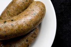 three sausages on a white plate sitting on a table