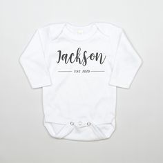 a white baby bodysuit with the name jackson printed on it